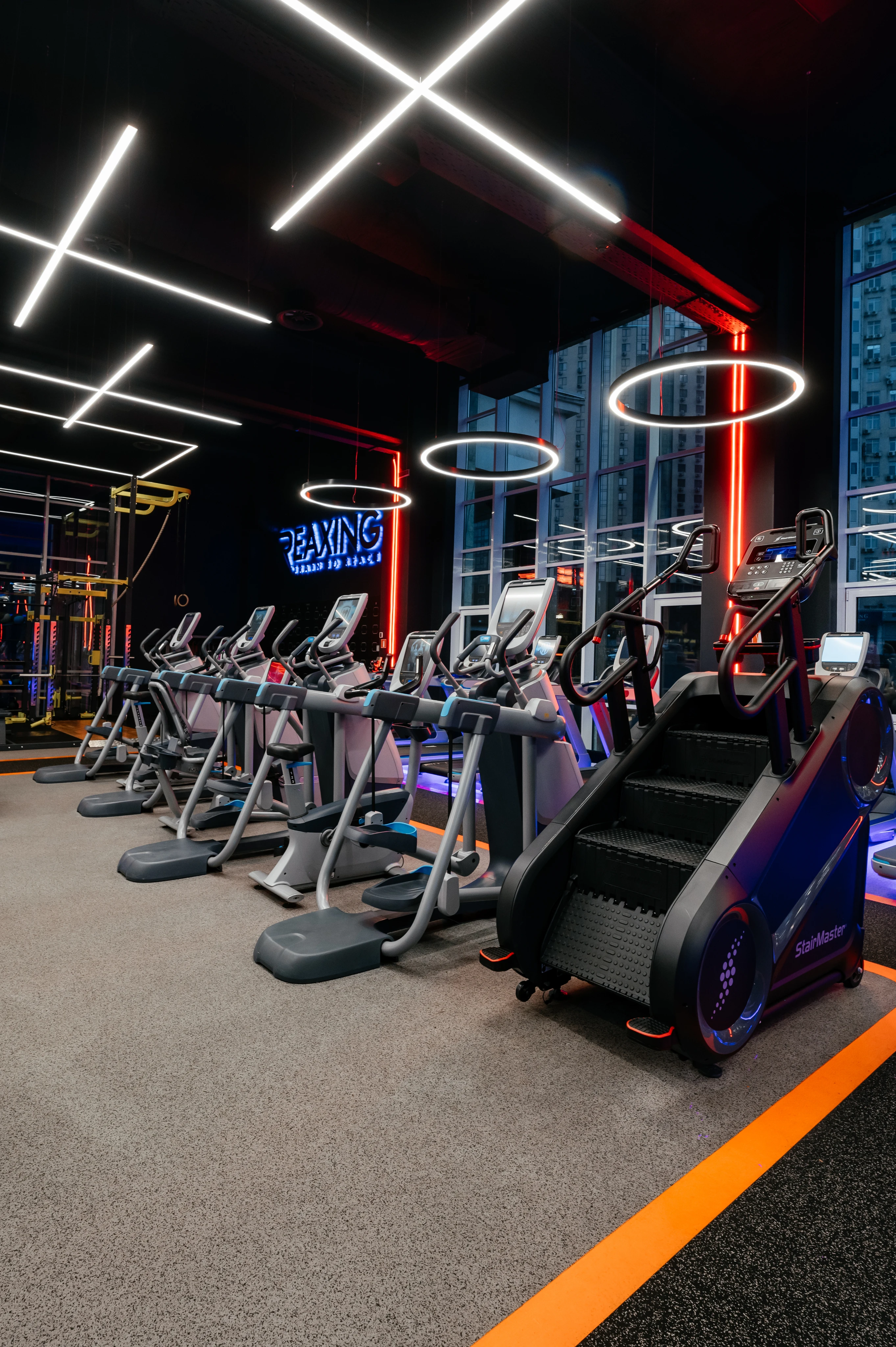 Сучасна тренажерна зала з тренажерами, неоновими вивісками та яскравим освітленням